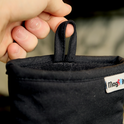 Black fabric oven mitt with a cloth loop being held by a hand.