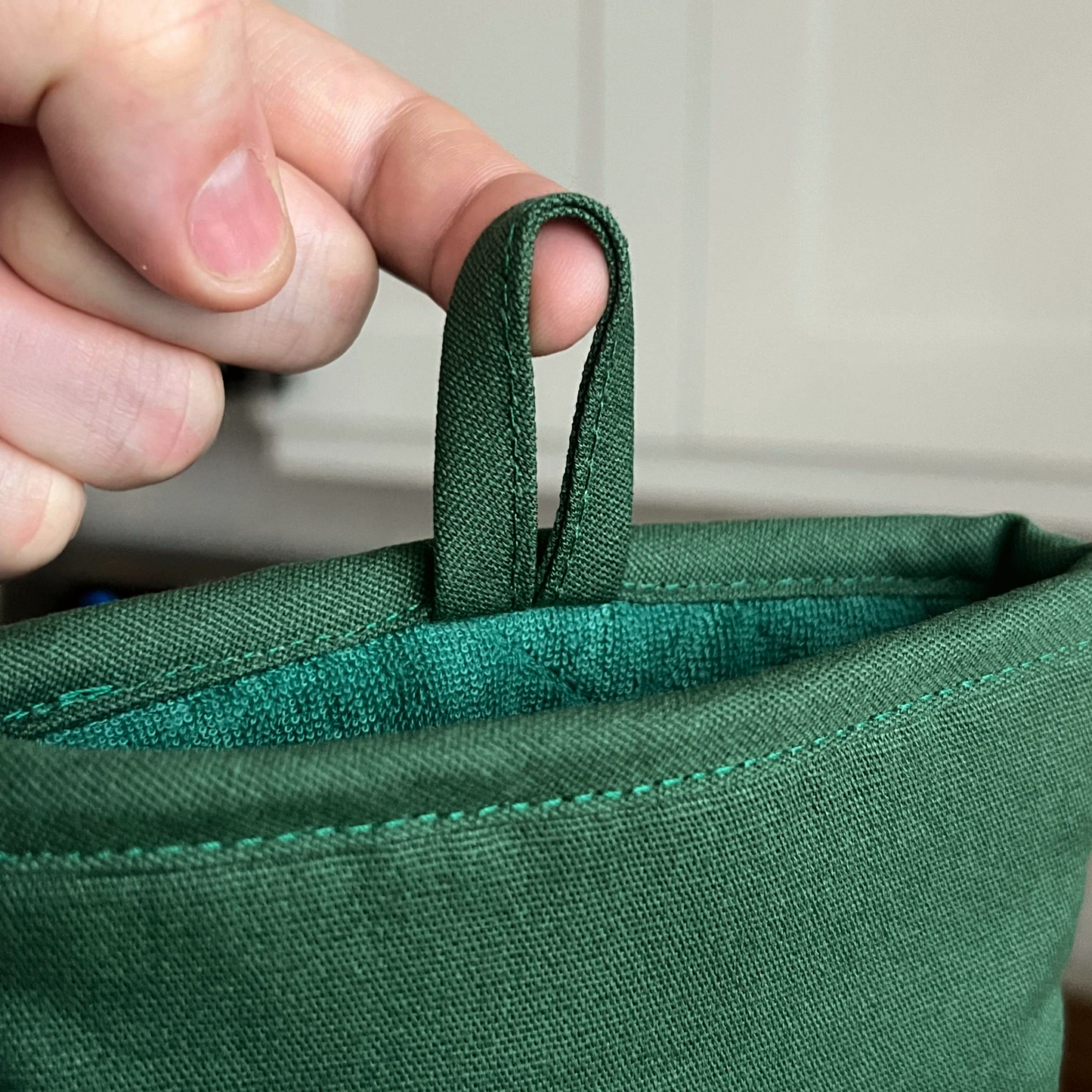 Hand holding a green fabric loop of a bag