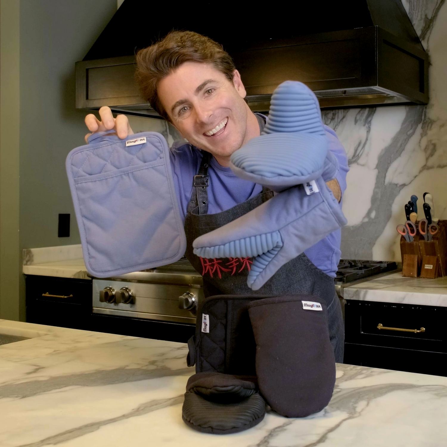Person in a kitchen holding blue pot holders and oven mitts