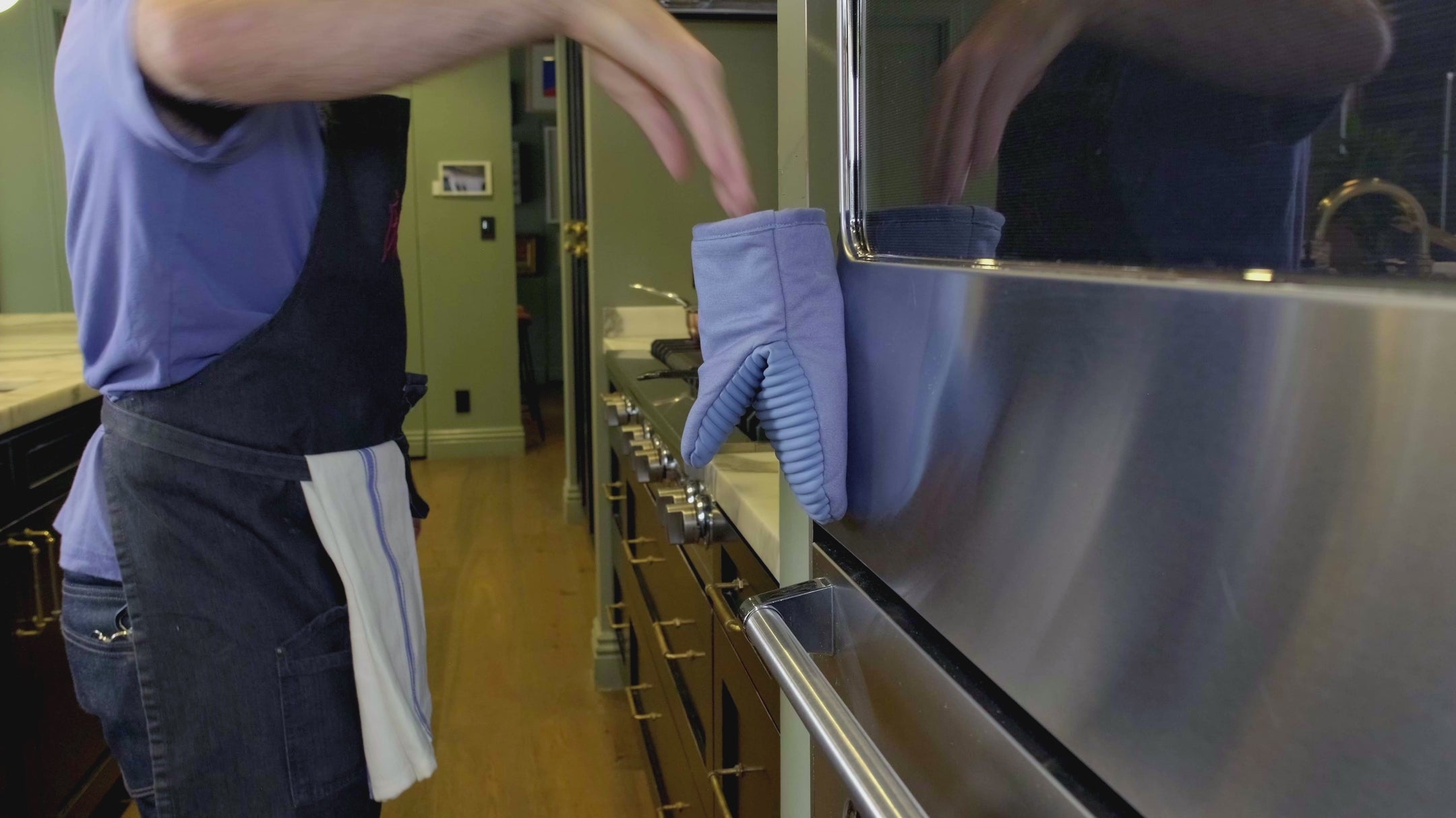 Load video: Man puts on oven mitt with one hand, handles a hot pan, and puts the mitt magnetically back onto the oven door.